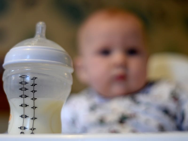 Toddler boy drinking milk from baby bottle stock photo - OFFSET